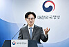 South Korean government official speaking at a podium beneath the national government emblem.