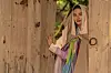 NANA as Hui-yeon peers through a wooden doorway in a colorful period costume.