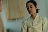NANA as Hui-yeon in a cream traditional-style garment, facing another person indoors.