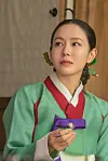 Son Ye-jin as Lady Cho wears a green and red hanbok and holds a purple ribbon indoors.