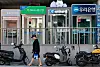 Outdoor bank ATMs and Korean bank signs line a Seoul sidewalk behind parked scooters.