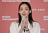 Kim Min-ha holds a microphone before a Busan International Film Festival backdrop.