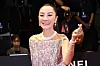 Michelle Yeoh smiles in a shimmering dress while making a K-heart gesture on the BIFF red carpet.