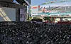 Large crowd seated outside Busan Cinema Center beneath a screen promoting a film festival open talk.