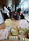 Pistachio rice cake packages sit in the foreground while shoppers queue inside a GS25 store.