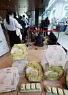 Pistachio rice cake packages sit in the foreground while shoppers queue inside a GS25 store.
