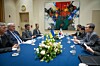 Delegates sit around a conference table with flags, flowers and an abstract painting behind them.