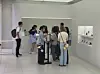 A group of visitors examines an exhibition in a bright modern gallery.