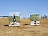 Two display panels stand in a dry field beneath a clear blue sky.