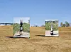 Two display panels stand in a dry field beneath a clear blue sky.