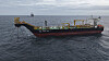 A colorful commercial workboat sails across dark, choppy sea beneath an overcast sky.