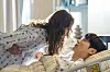 Na Bo-bae leans over Baek Ho-rang as he rests in a hospital bed.