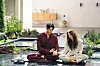 Kim Young-kwang and Chae Soo-bin sit together beside a landscaped pool in a sunlit courtyard.