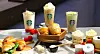 Starbucks drinks and assorted pastries arranged on a table with a central platter of bread rolls.