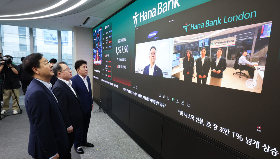Then-Finance Minister Koo Yun-cheol, first from left, speaks via video call with employees at Hana Bank's London branch during a visit to the dealing room at the bank's headquarters in Jung District, central Seoul, on July 6, the first day of 24-hour foreign exchange trading in Korea.