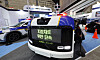 Compact blue-and-white autonomous patrol vehicle displayed at a police technology expo booth.